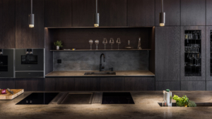 Ett kök med mörk inredning och corian lava rock bänkskiva med en köksö i förgrunden